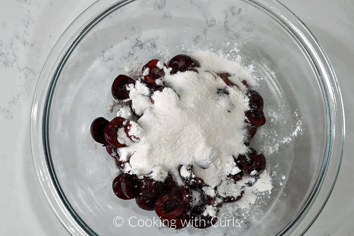 Fresh cherries in a mixing bowl with sugar and arrowroot starch. 