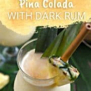 Looking down on two cocktail glasses filled with frozen Pina colada with dark rum floating on top and pineapple wedge and leaves as garnish and title graphic across the top.