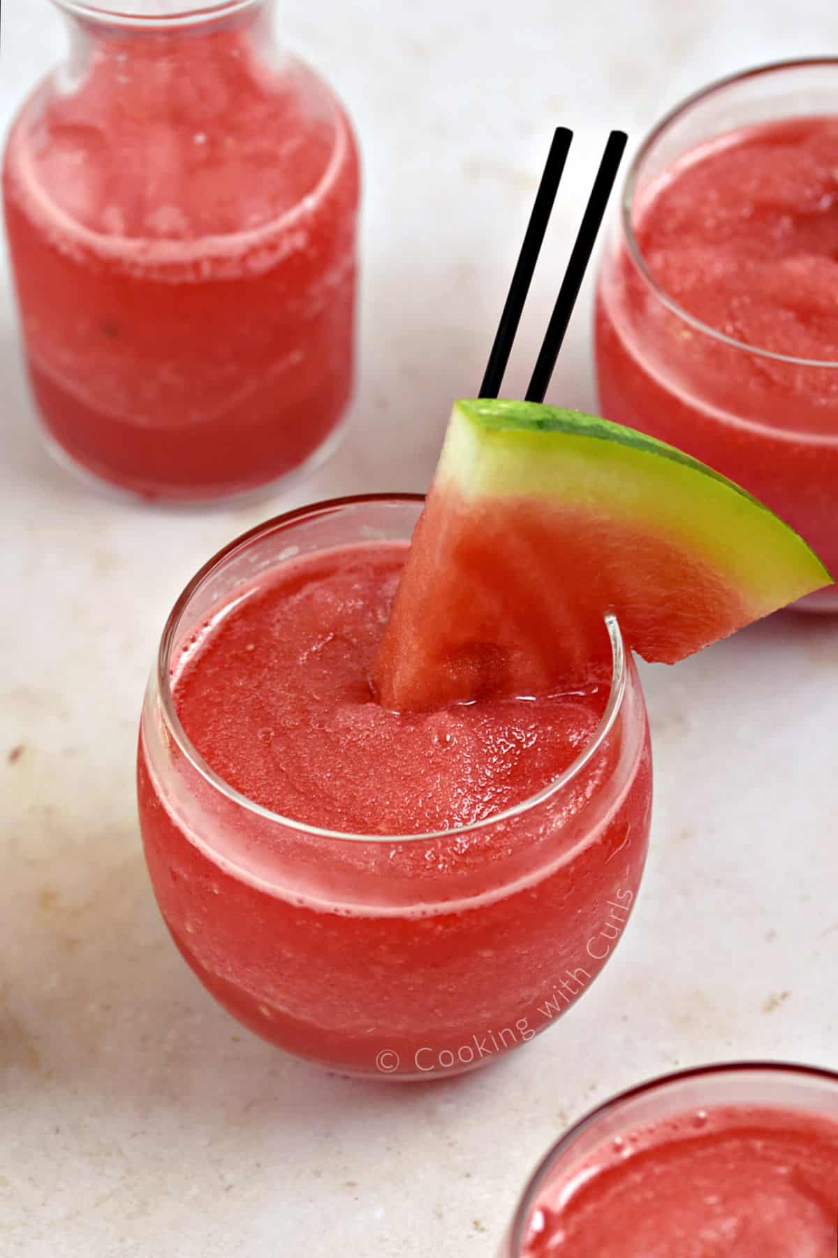 Three small glasses filled with frozen watermelon wine smoothie garnished with watermelon wedges.