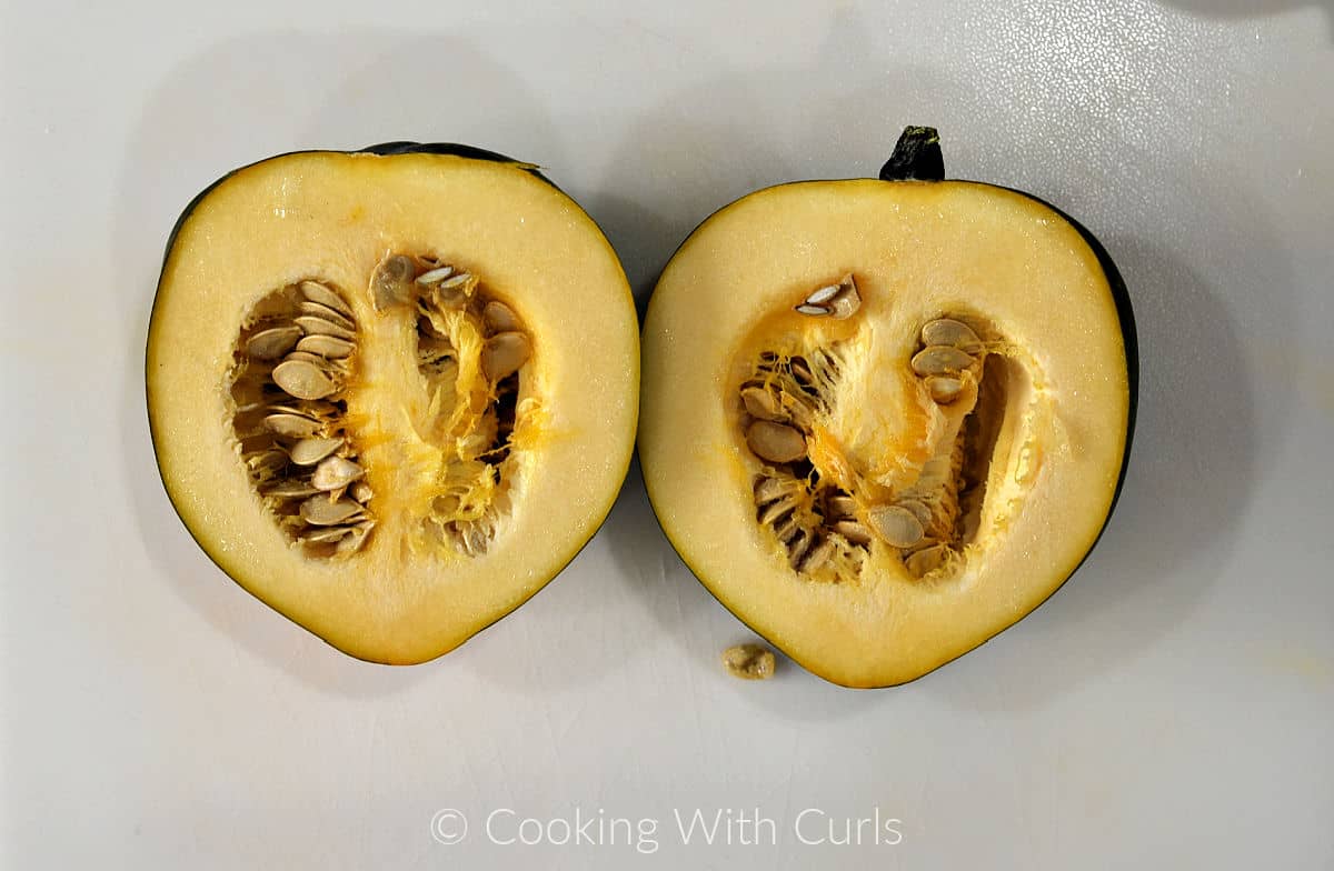 An acorn squash cut in half to show seeds inside. 