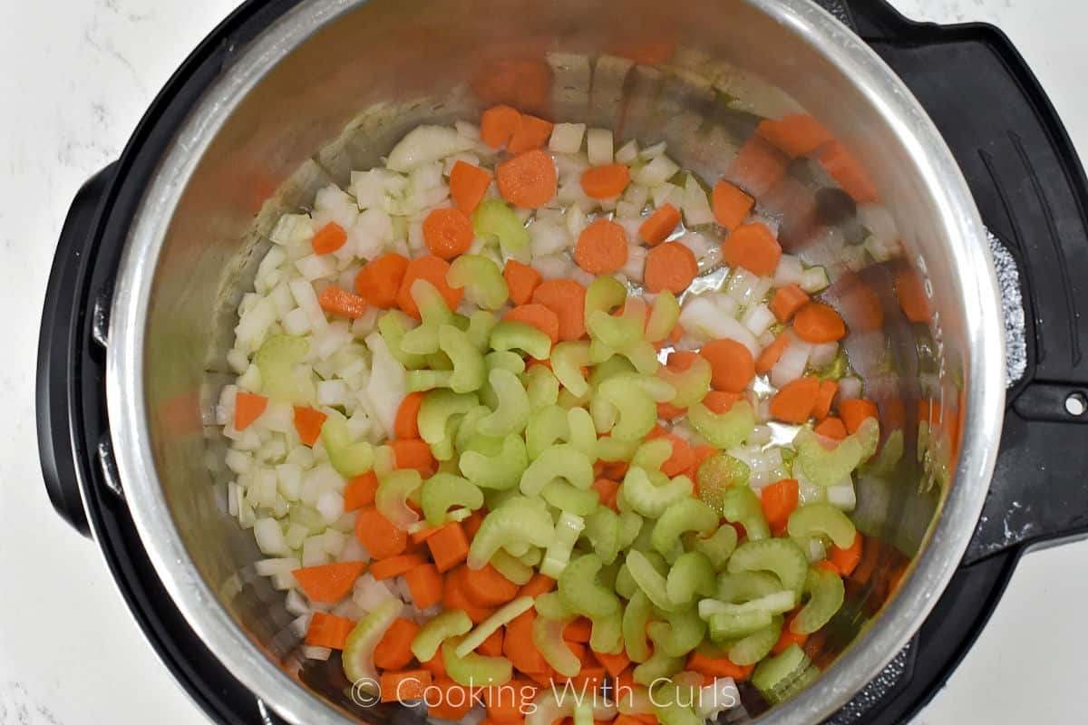 Chopped onion, carrots, and sliced celery in a pressure cooker. 