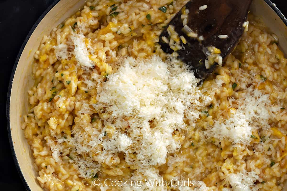 Grated parmesan cheese on top of the risotto mixture in a skillet. 