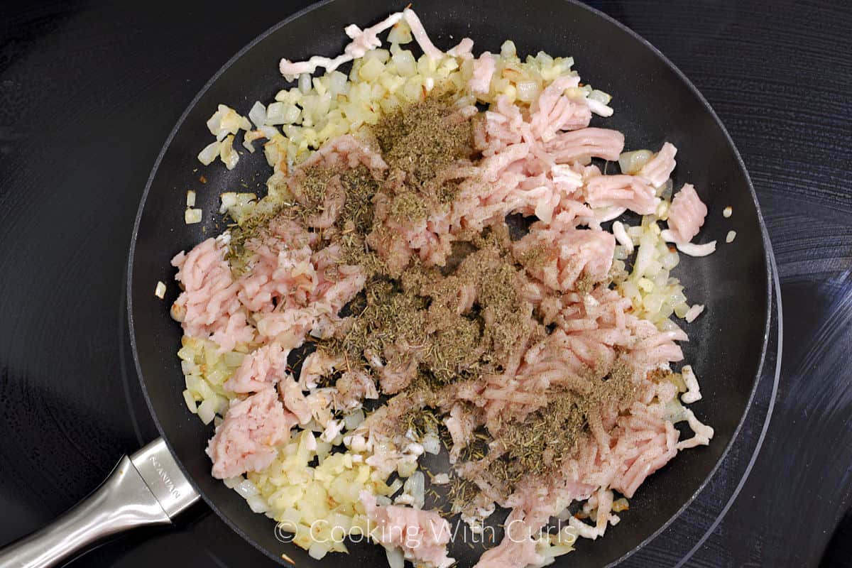 Ground turkey and seasonings in a skillet with the cooked onion. 