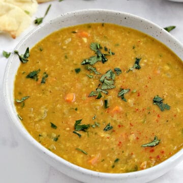 Two bowls of red lentil soup topped with chopped cilantro.
