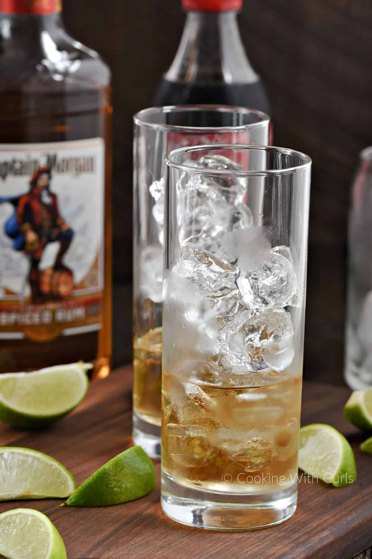 Two highball glasses filled with ice cubes and two ounces of spiced rum. 