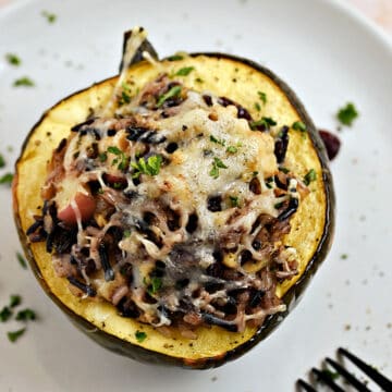 Wild Rice Stuffed Acorn Squash with apples, turkey, and cranberries on a plate.