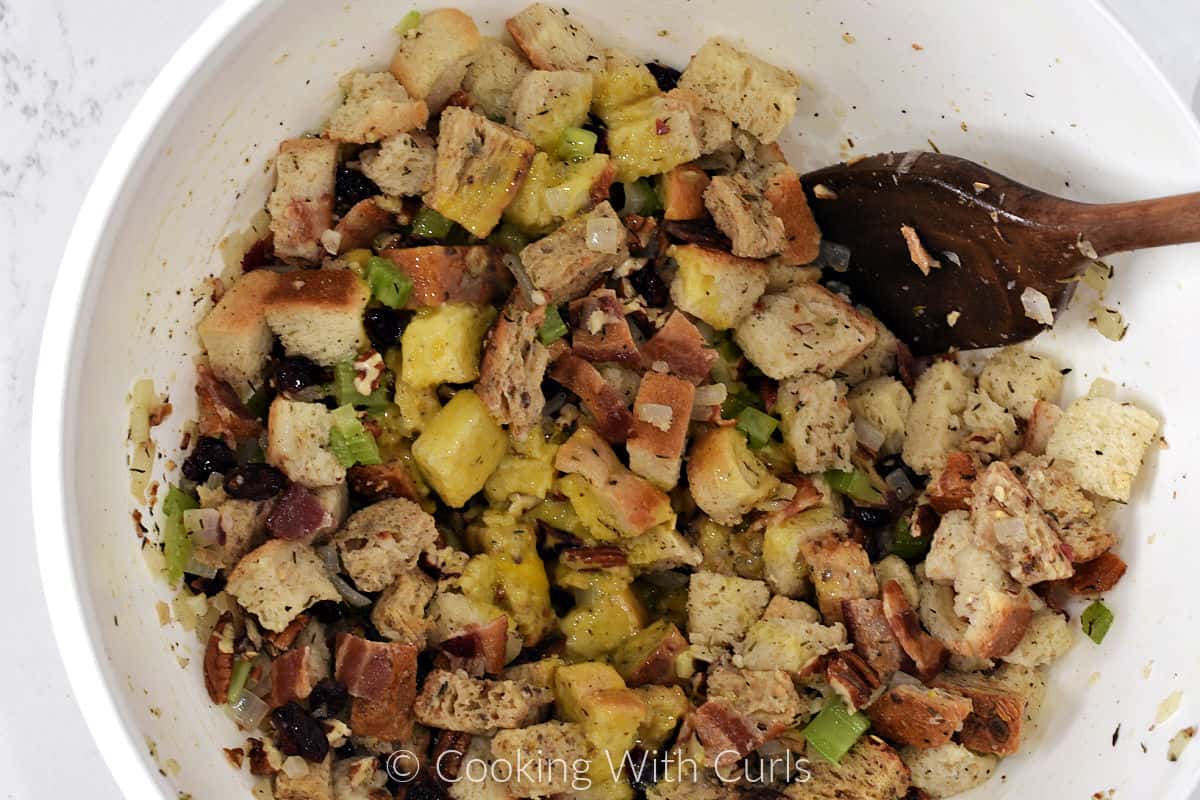 All stuffing ingredients mixed together in a bowl with a wooden spoon.