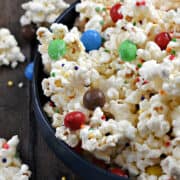 A bowl filled with white chocolate popcorn with colored sprinkles and m&ms.