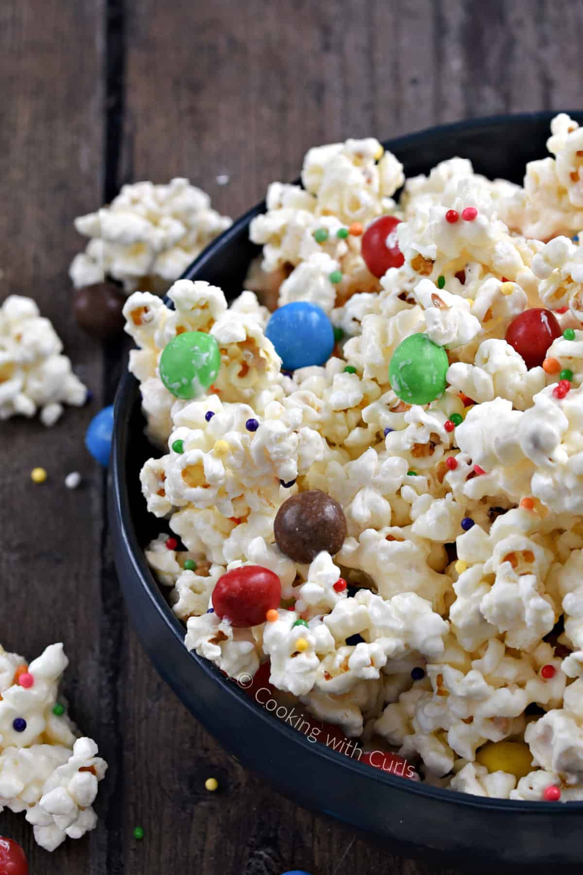 A bowl filled with white chocolate popcorn with colored sprinkles and m&ms. 