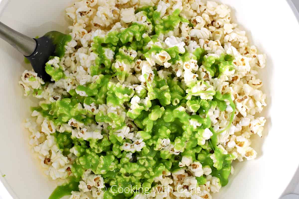 Green marshmallow mixtures poured over popcorn in a large bowl. 