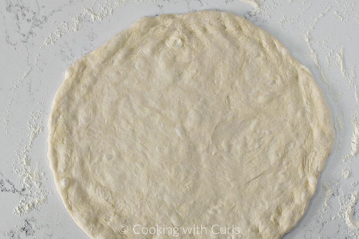Pizza dough crust on a floured surface. 