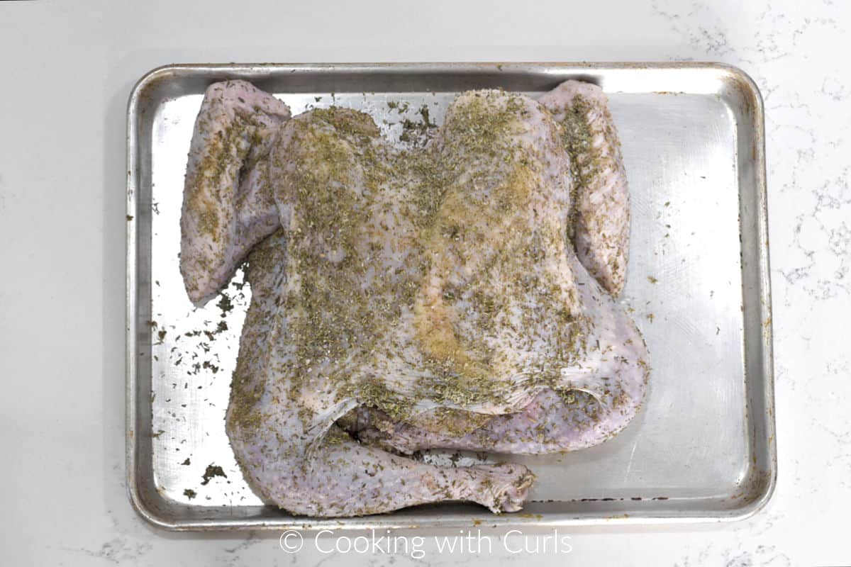 Seasoned, butterflied turkey on a baking sheet. 