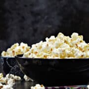 Two bowls filled with wasabi seasoned popcorn recipe with chop sticks and popcorn scattered on the table.