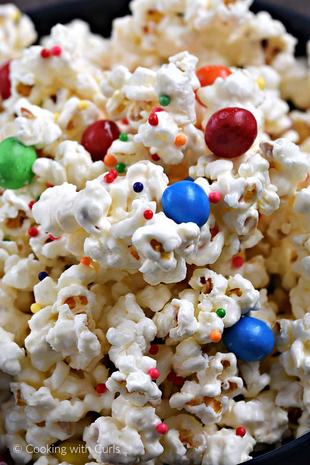 White chocolate covered popcorn  with M&Ms and colored sprinkles. 