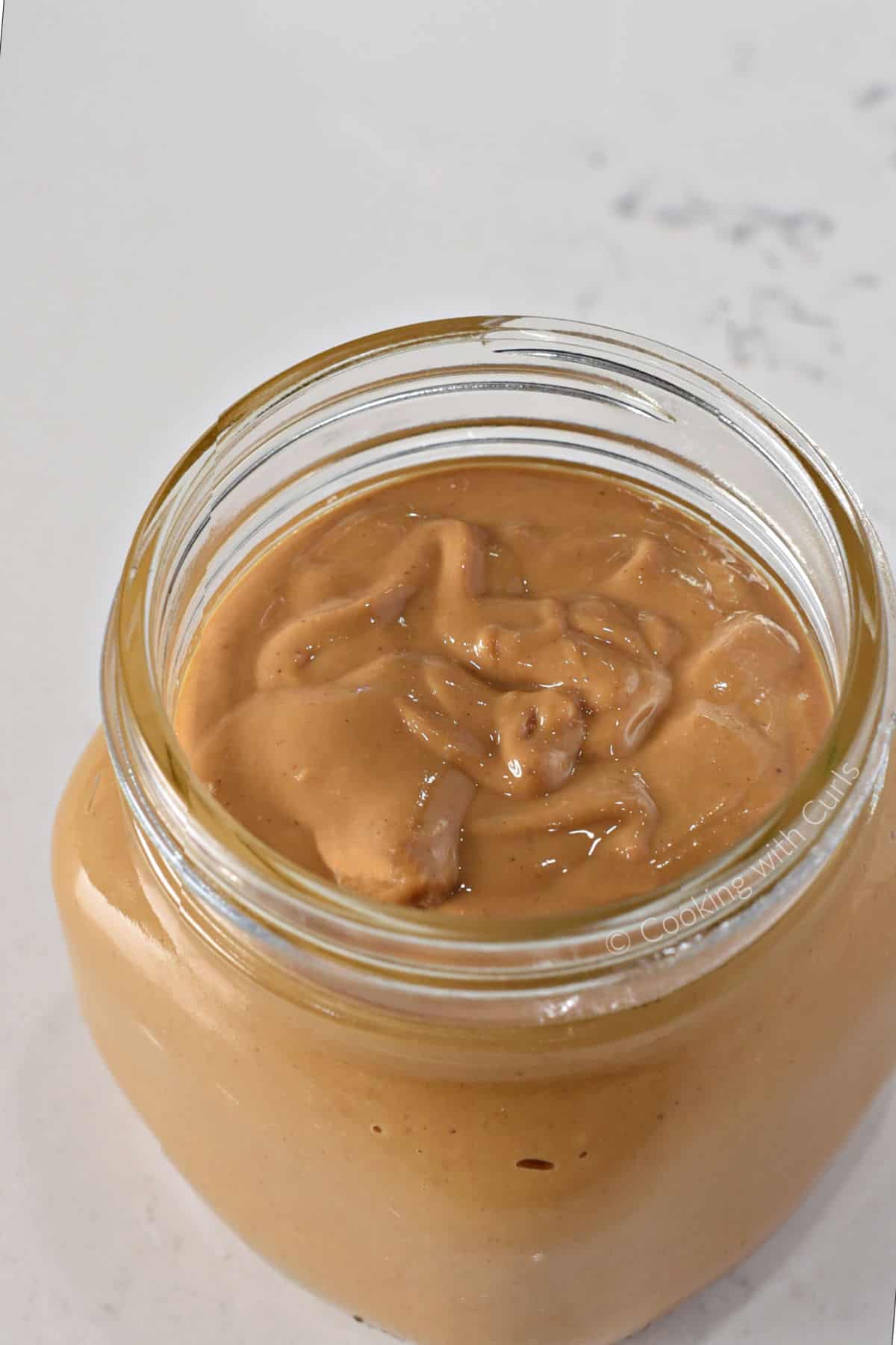 A square jar filled with homemade peanut butter. 