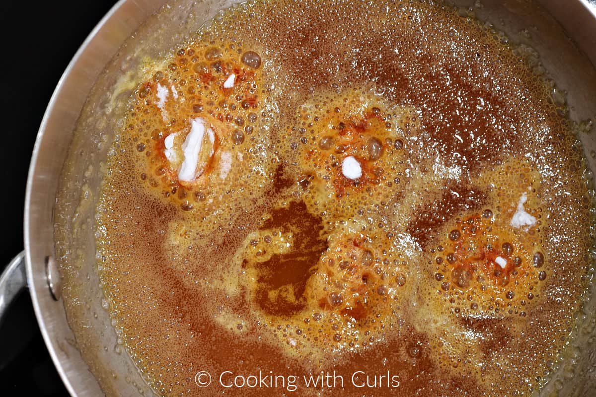 Baking soda and lemon flavoring added to the boiling caramel in a saucepan. 