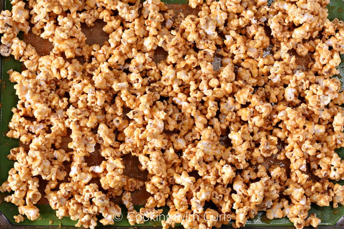 Honey lemon coated popcorn spread out on a silicone lined baking sheet. 