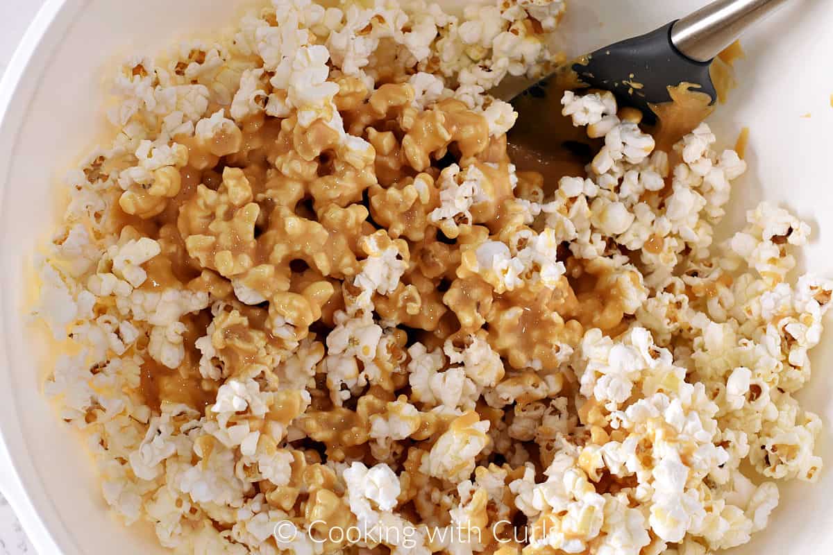 Honey lemon mixture poured over popped popcorn in a large bowl. 