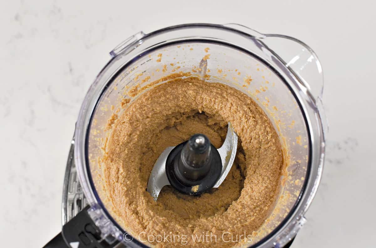 Pureed peanuts in the bowl of a food processor. 