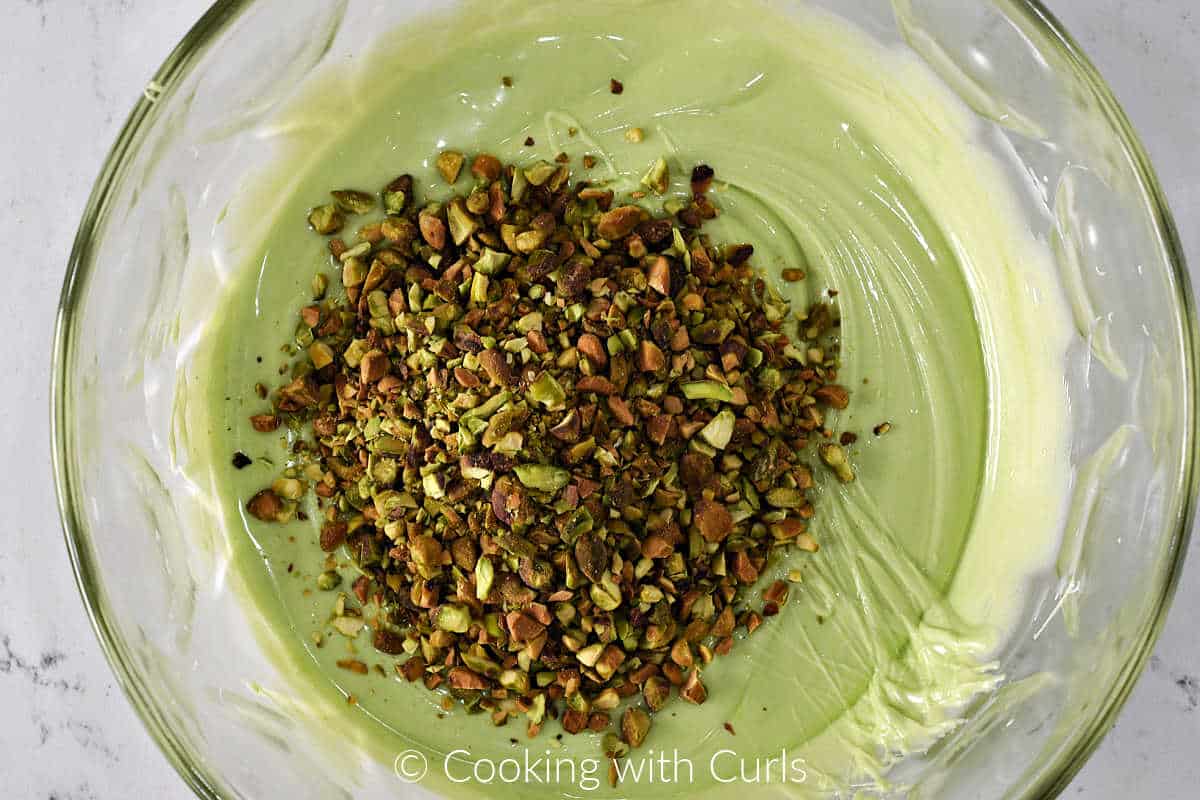 Chopped pistachios and green melted chocolate in a large mixing bowl. 