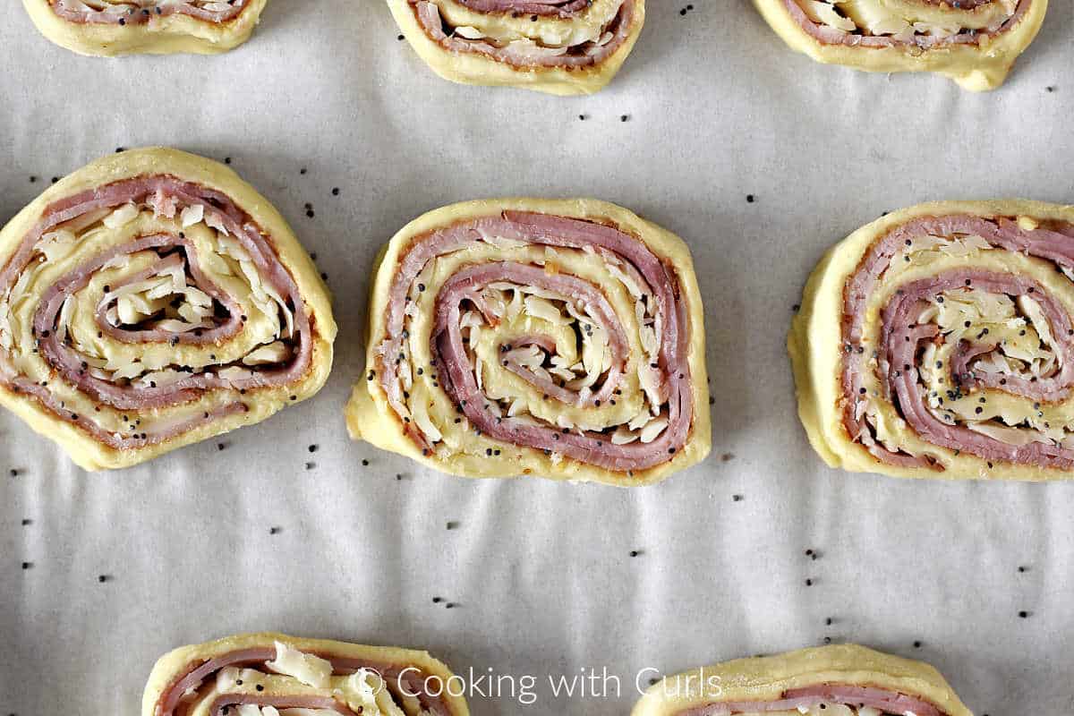 Eight-puff-pastry-wrapped-ham-and-cheeser-pinwheels-on-a-parchment-lined-baking-sheet.