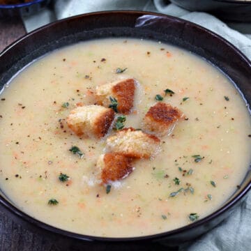 A bowl of Irish vegetable soup topped with sourdough croutons and fresh thyme.