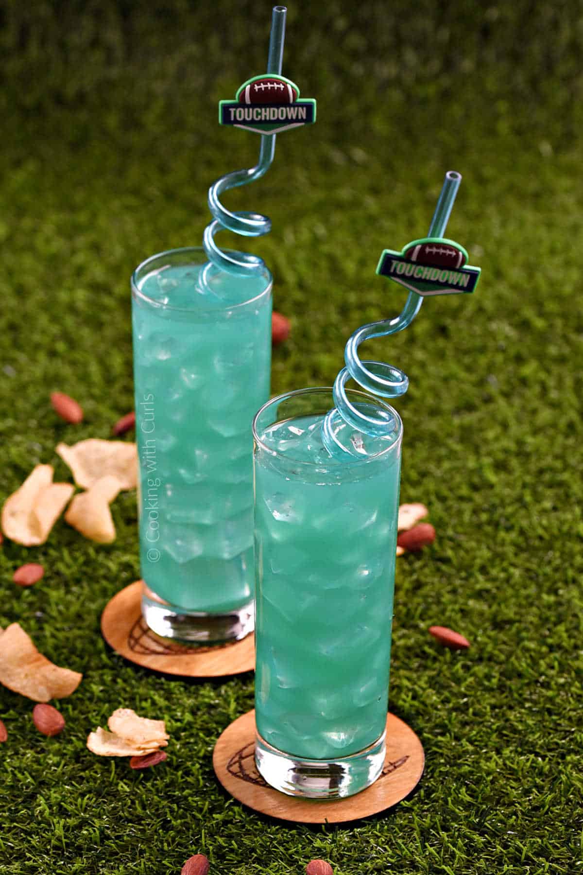 Teal green drinks in two, skinny cocktail glasses with spiral straws.