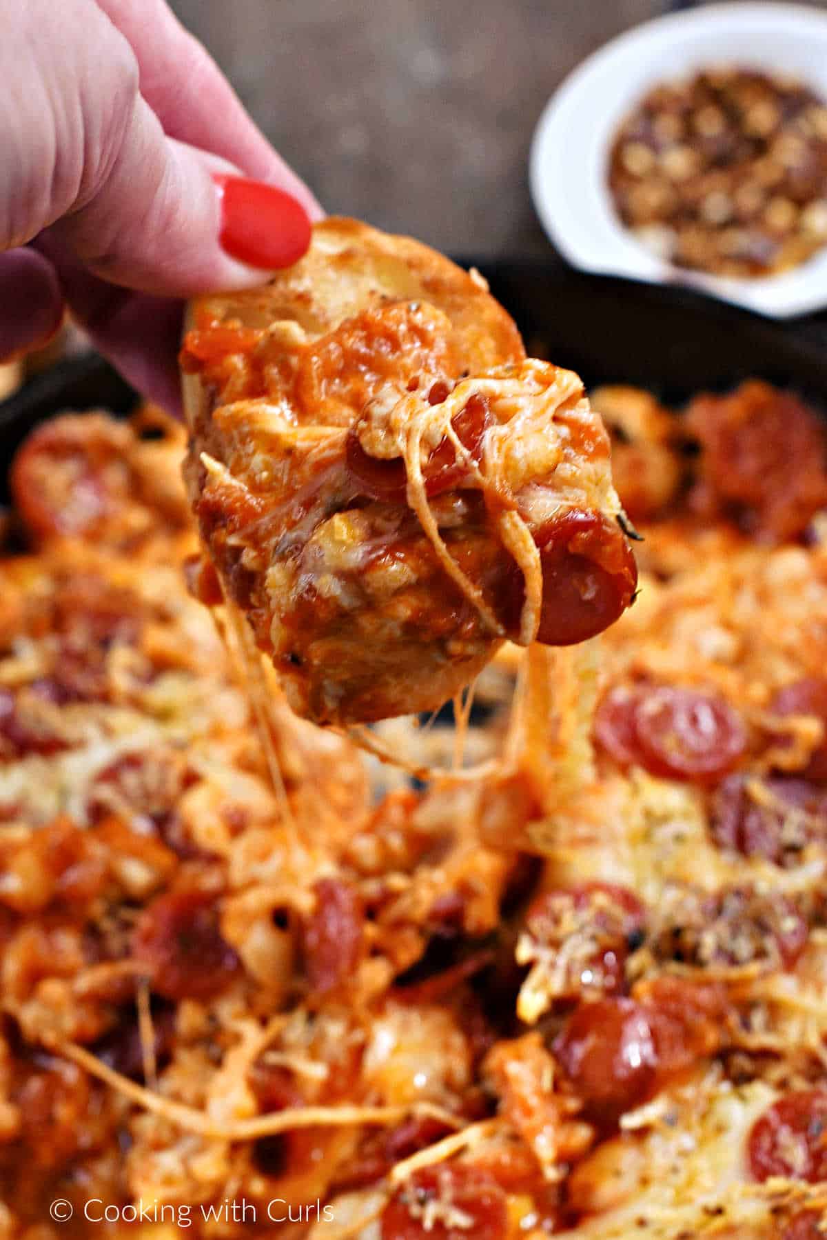 Pizza-dip-on-crostini-held-above-the-pan.