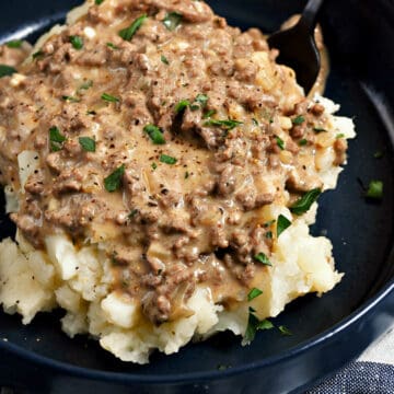 A-bowl-of-mashed-potatoes-topped-with-Hamburger-Gravy-and-chopped-parsley.