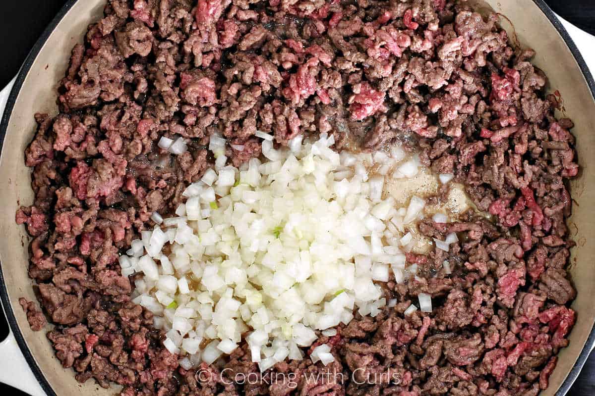 Chopped-onion-in-the-center-of-ground-beef-in-a-skillet.
