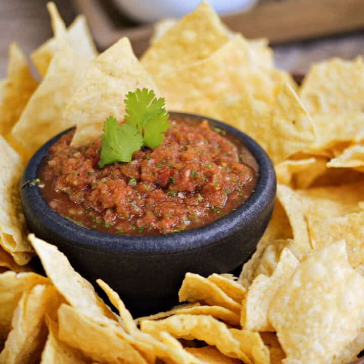 A bowl of restaurant-style blender salsa surrounded by tortilla chips. 