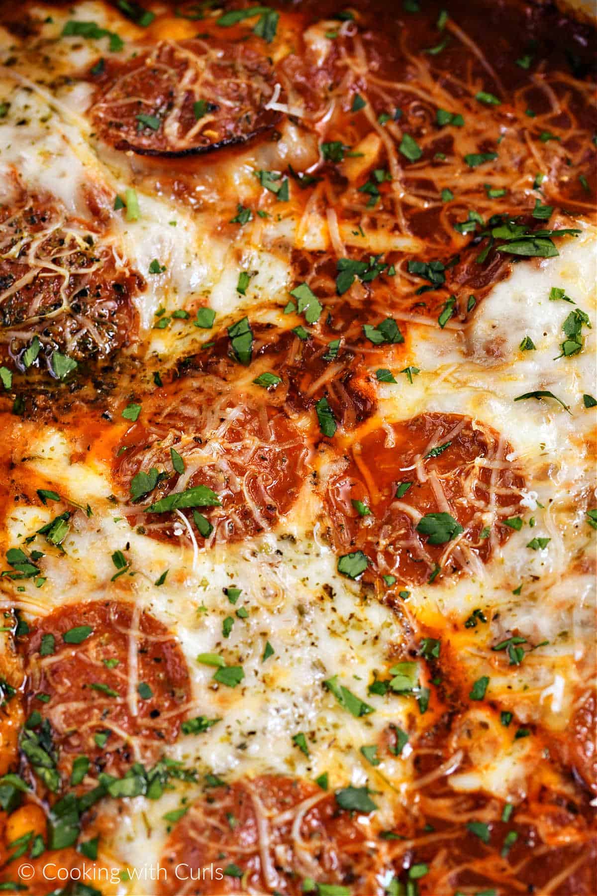 Chicken breasts topped with melted cheese, slices of pepperoni, grated parmesan and chopped parsley.
