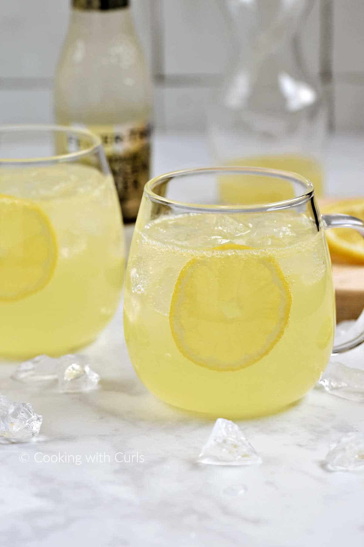Limoncello, vodka, lemon juice, ice cubes, and ginger beer with a lemon slice in glass mugs.