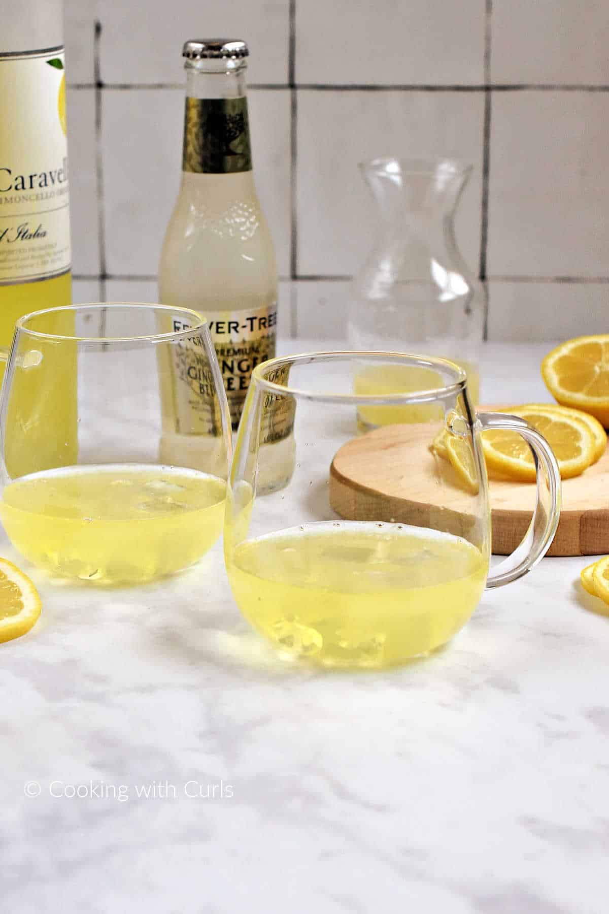 Limoncello, vodka, lemon juice, and a few ice cubes in two glass mugs.