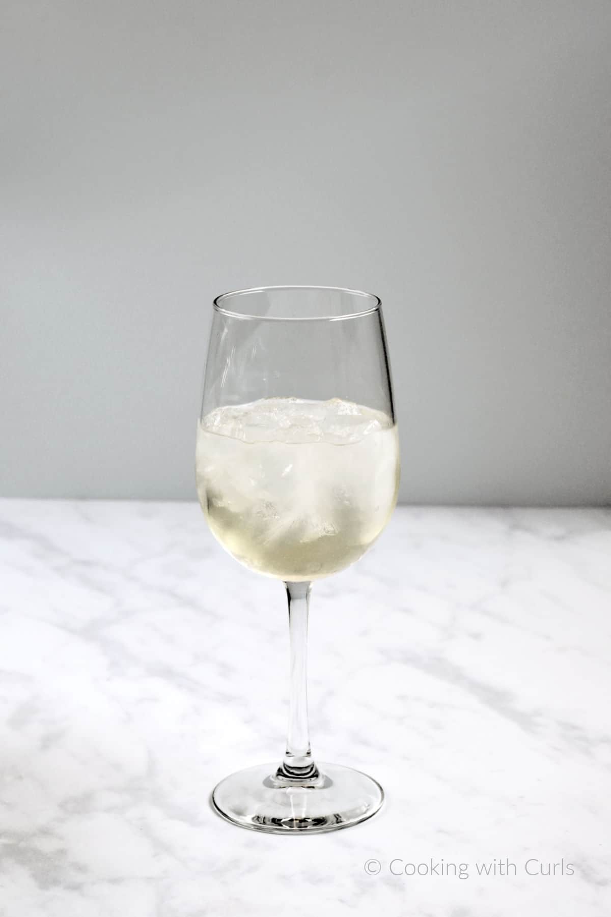 Moscato wine, elderflower liqueur, white grape juice, and ice cubes in a wine glass.