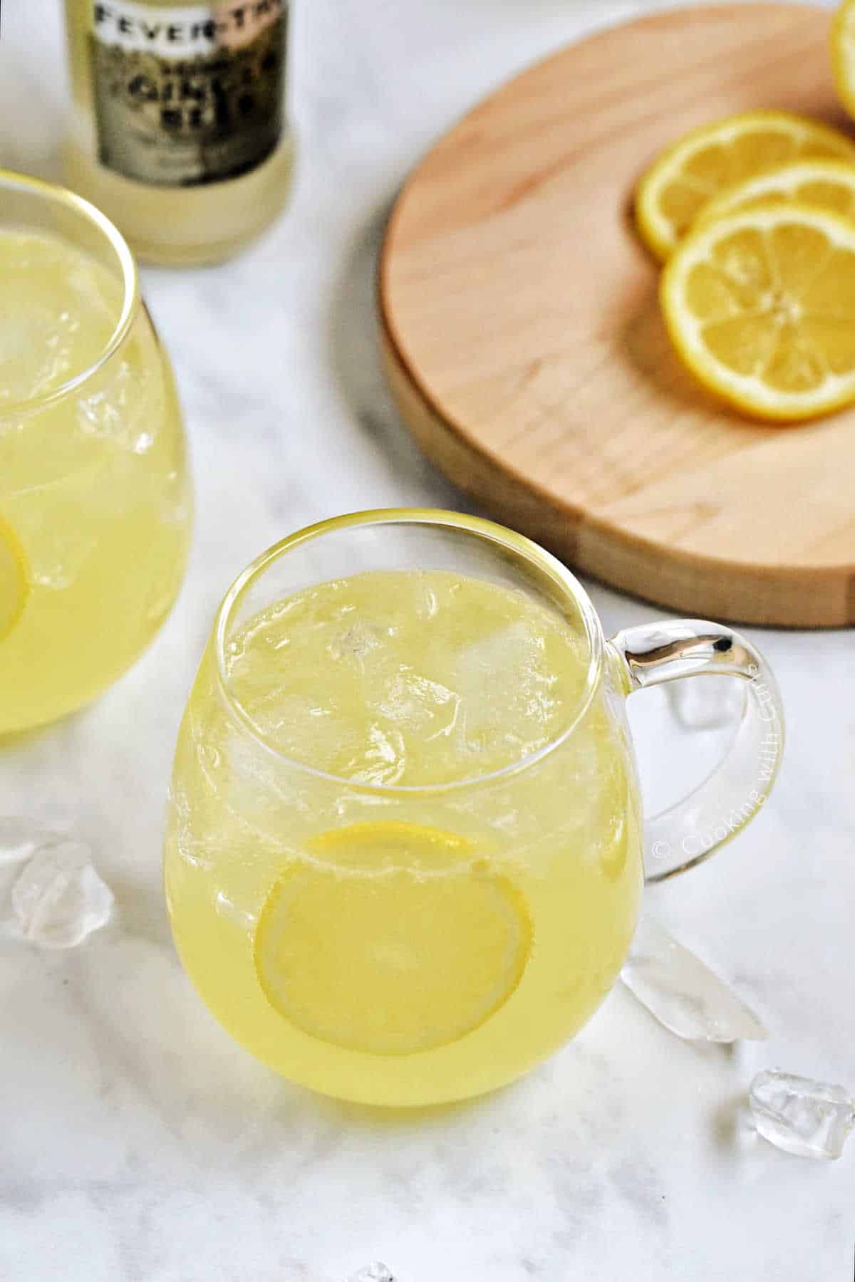 Two Limoncello Moscow Mules in a glass mug with ice and lemon wheel garnish.