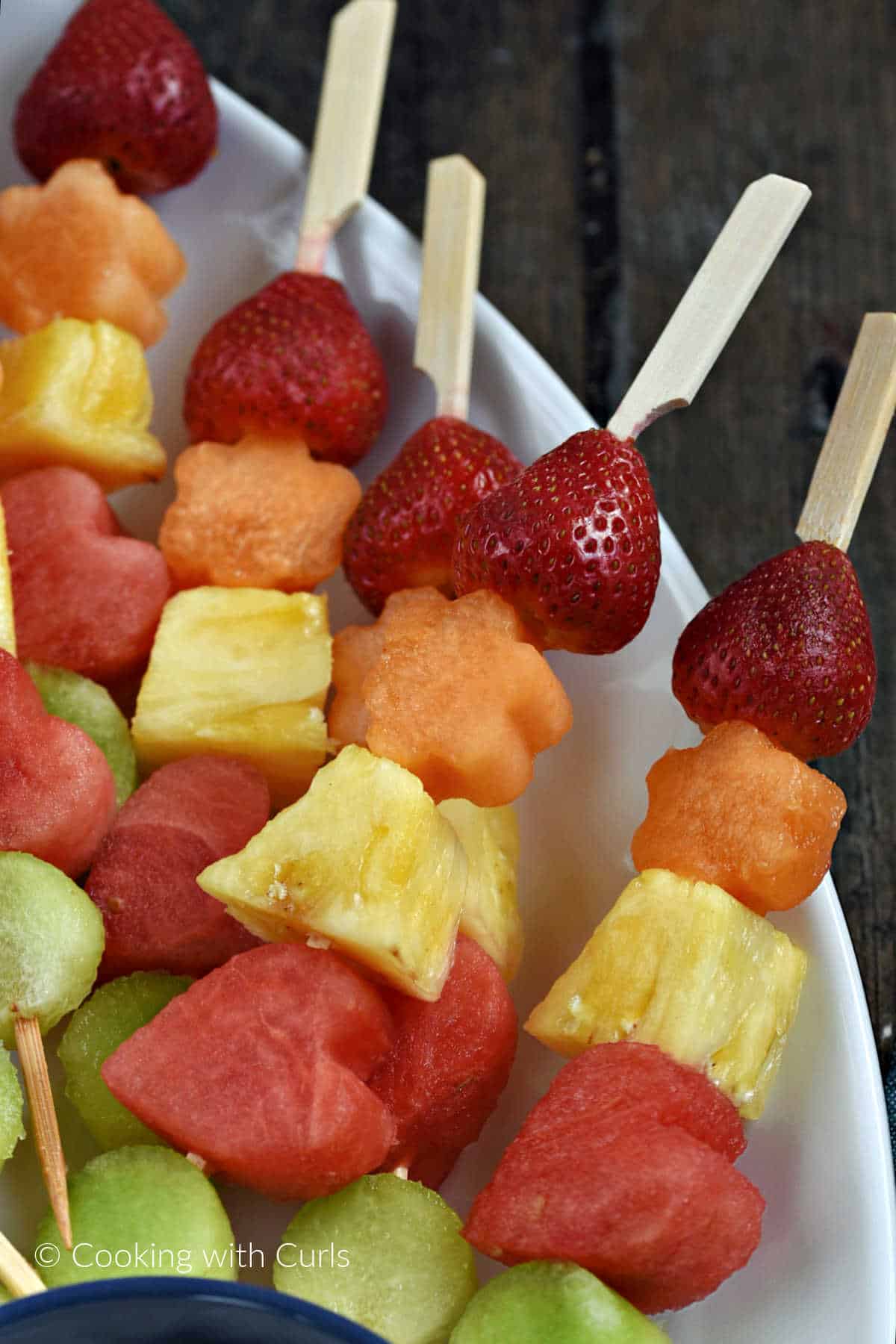 Fresh fruit on wooden skewers laying on a serving platter.
