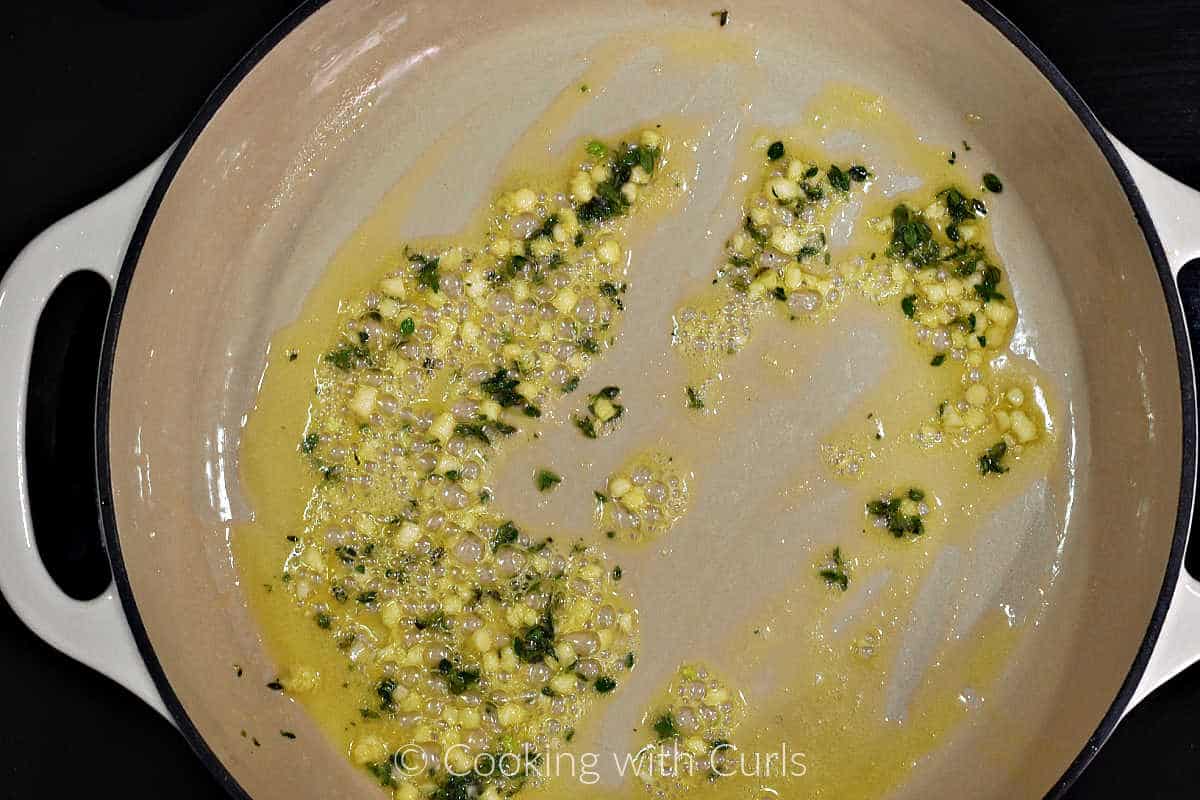 Olive oil, butter, minced garlic, and thyme leaves cooking in a large skillet.