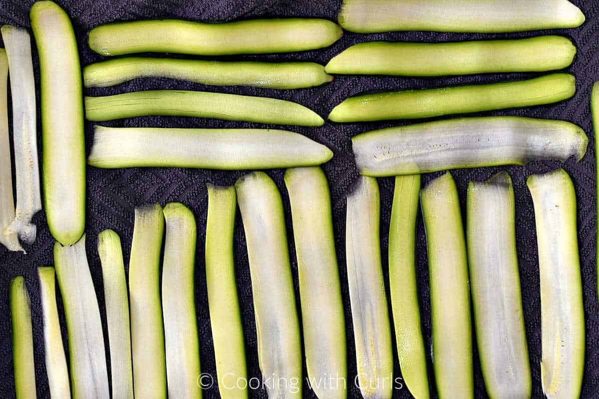 Zucchini ribbons laid out on a dish towel.