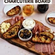 Italian deli meats and cheeses on a wood board with olives, mustard, and grilled bread with title graphic across the top.