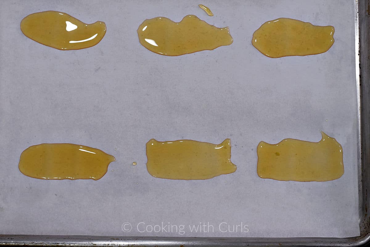 Six tablespoons of honey spread into rectangles on a parchment lined baking sheet.