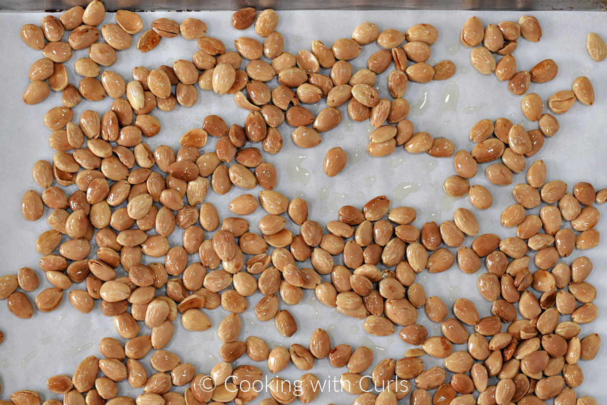 Sautéed almonds on a parchment lined baking sheet.