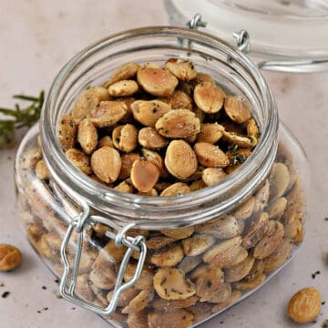 A lidded jar filled with roasted Marcona almonds tossed in sea salt and chopped rosemary.