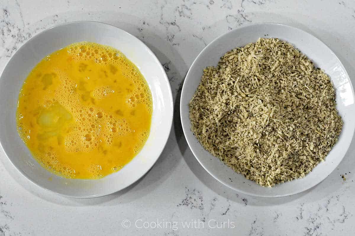 A bowl of egg wash and bowl of breading mixture.