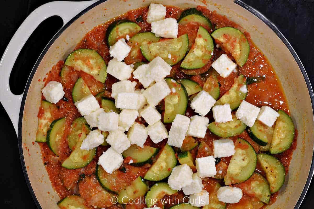 Cheese cubes and zucchini slices in tomato sauce.