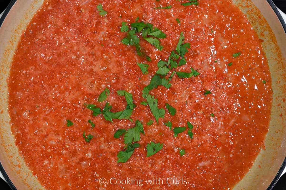 Tomato sauce and cilantro leaves in skillet.
