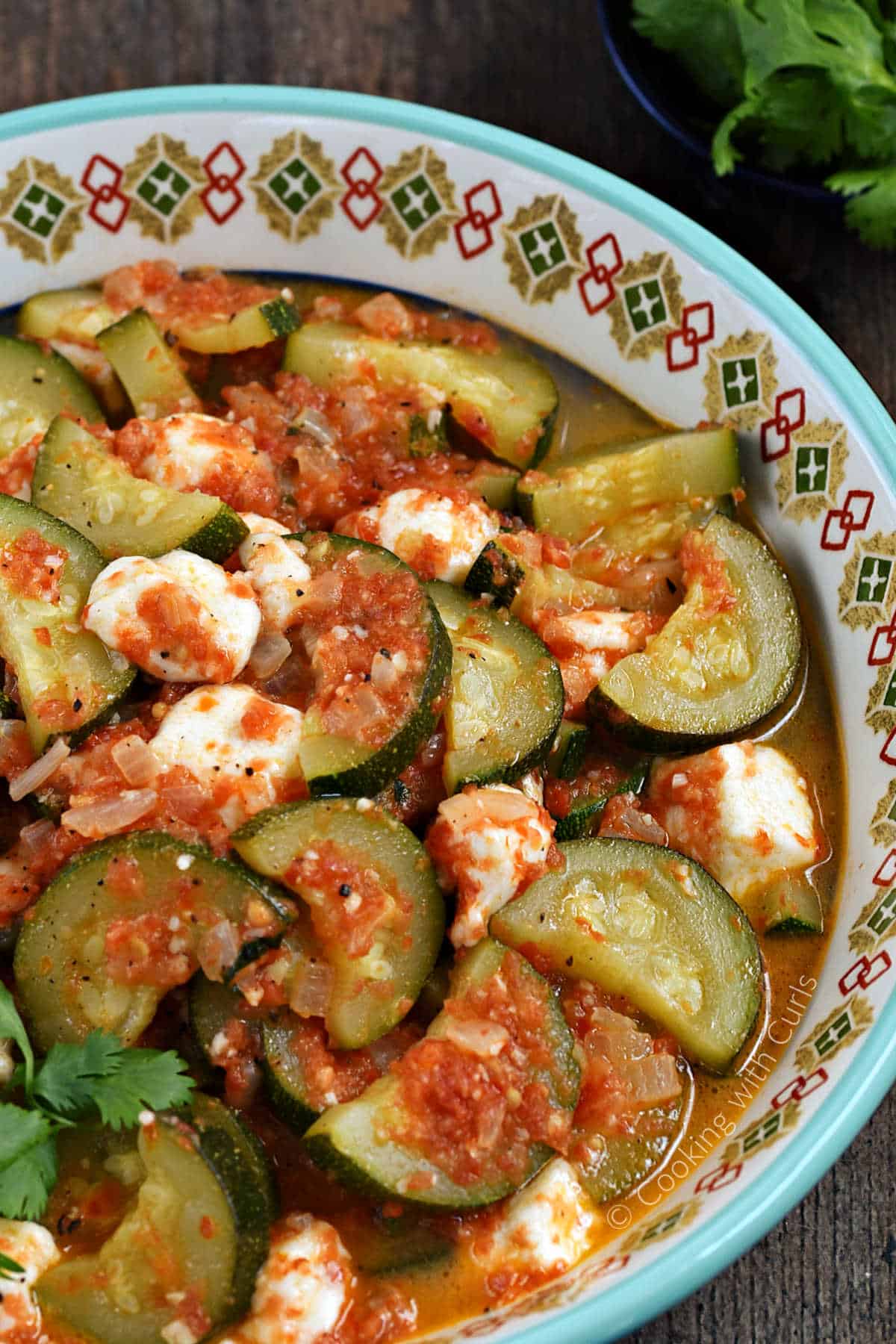 Cooked zucchini slices, melted cheese cubes, and tomato sauce in a bowl.