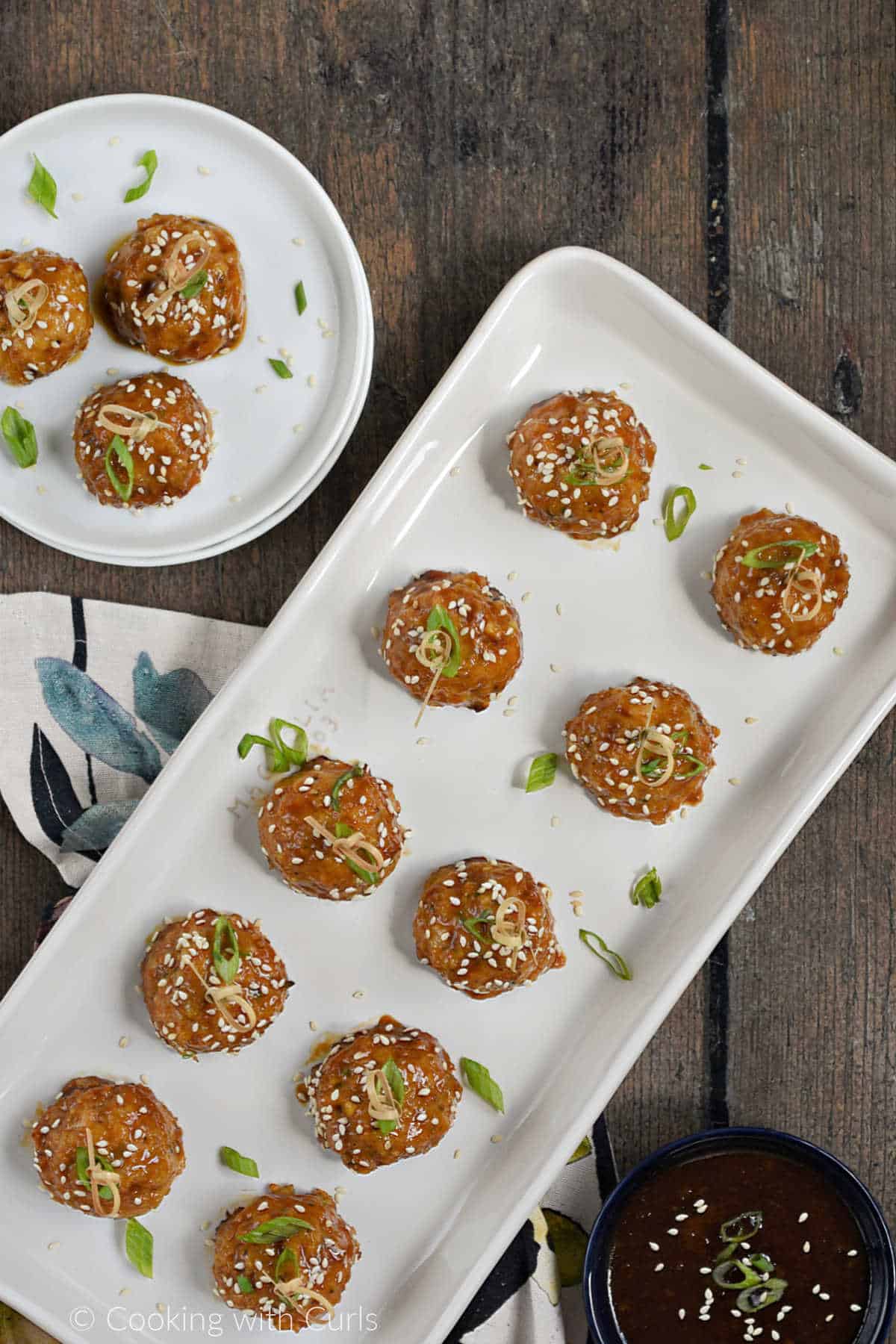 Ten teriyaki chicken meatballs on a platter, and three on a small plate.