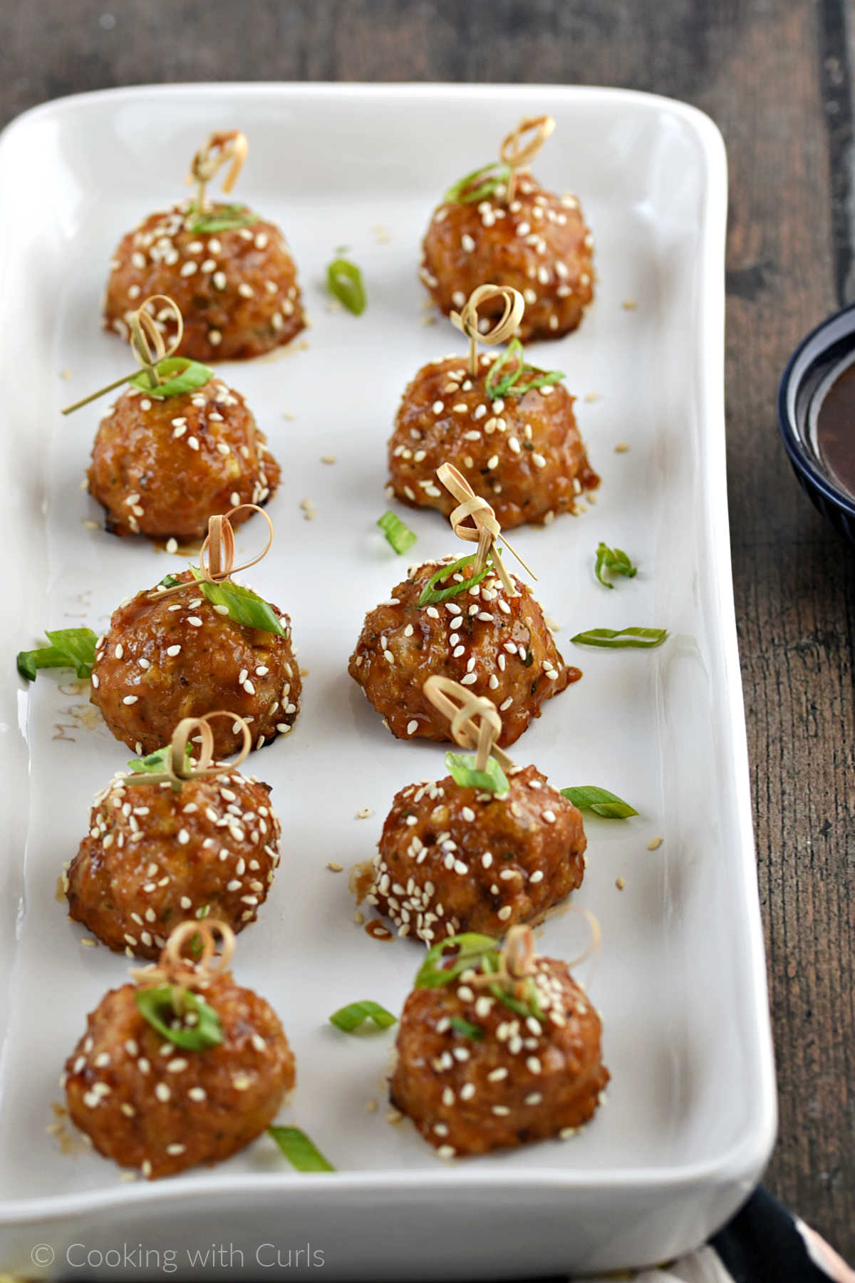 Ten baked teriyaki chicken meatballs on a serving platter.