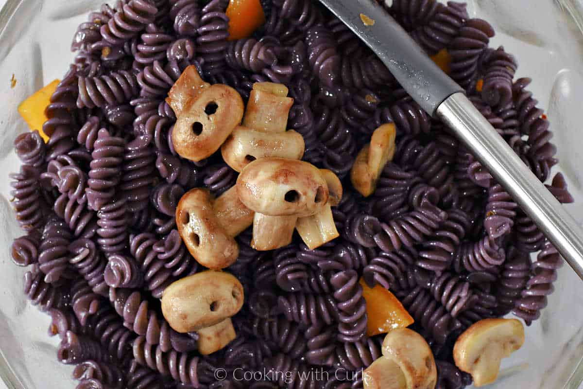 Spiral pasta, bell pepper triangles, Italian dressing, and mushroom skulls in a large bowl.